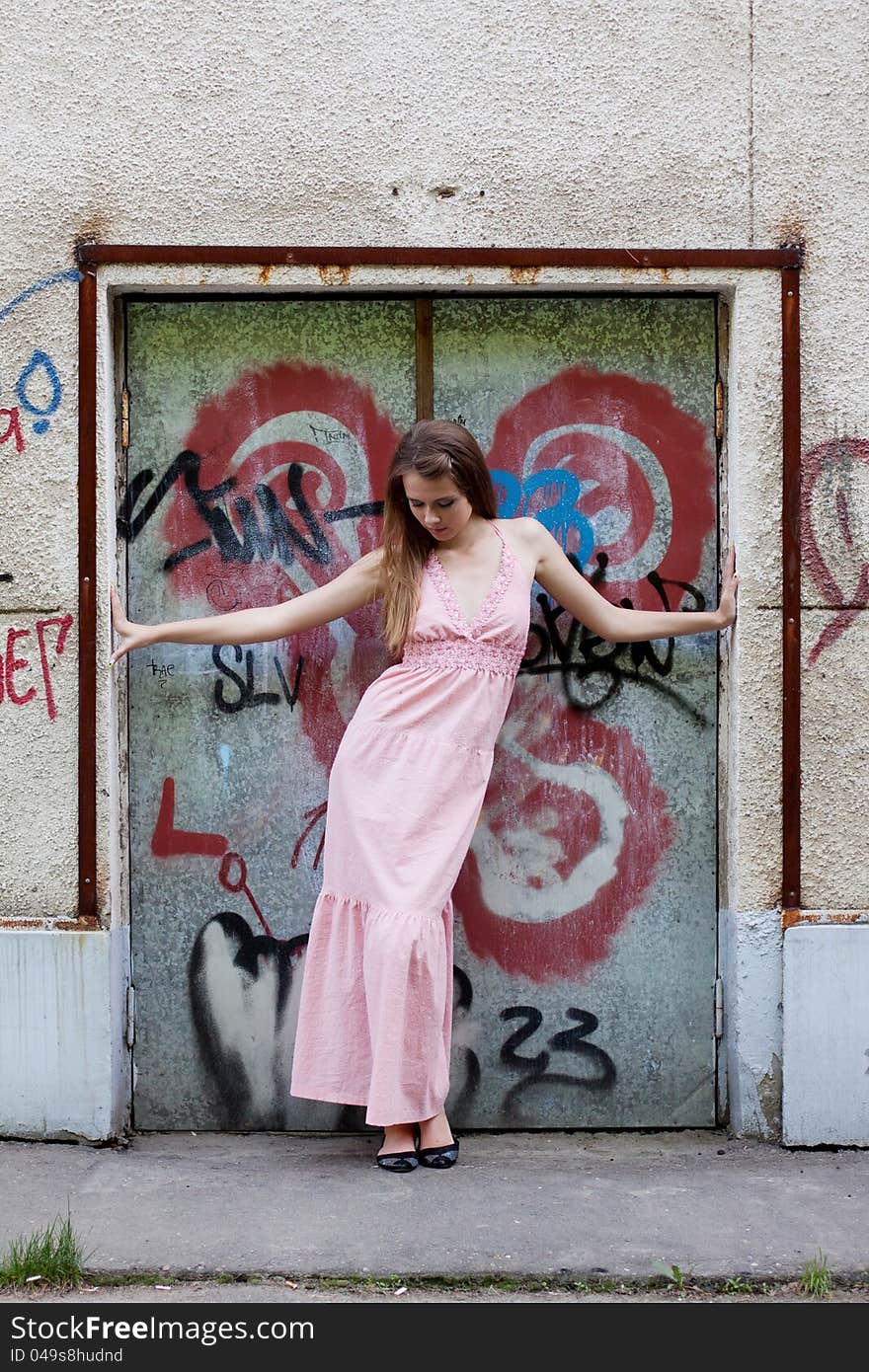 Beautiful young girl standing at the door with graffiti