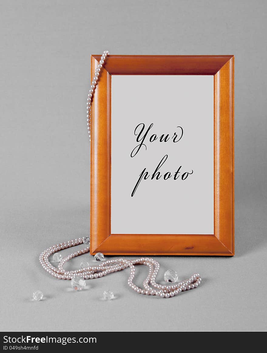 On the corner of wooden frame for a photo beads hang from pearls and hand down on the edge of scope. On the corner of wooden frame for a photo beads hang from pearls and hand down on the edge of scope