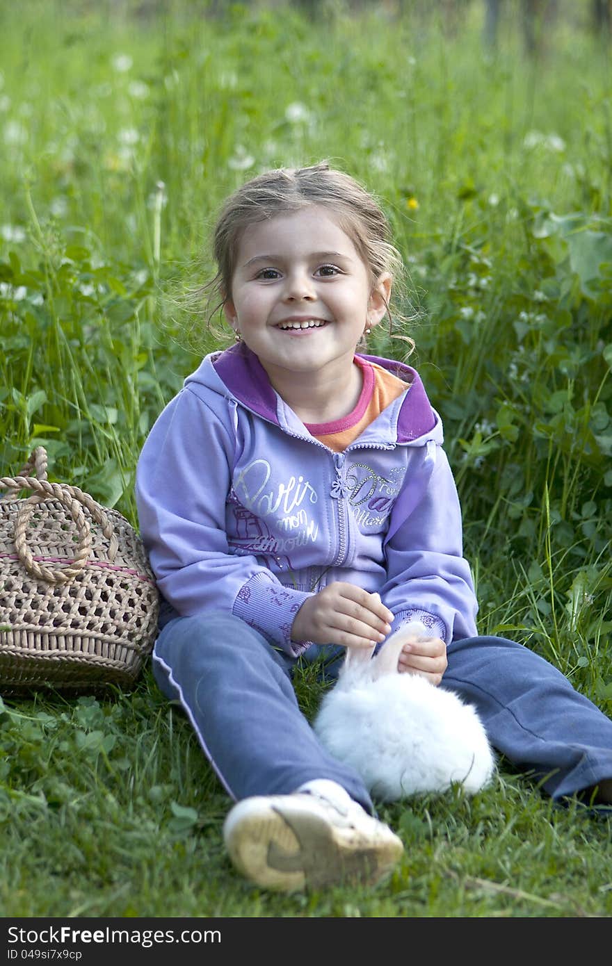 Little girl smiling with little white rabbit on the grass. Little girl smiling with little white rabbit on the grass