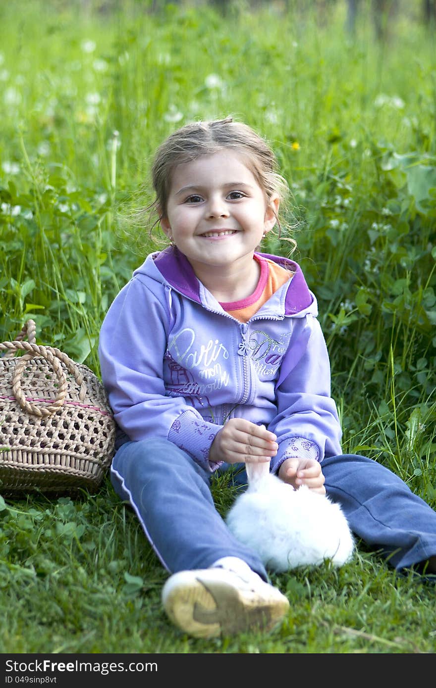 Little girl and white rabbit on the grass