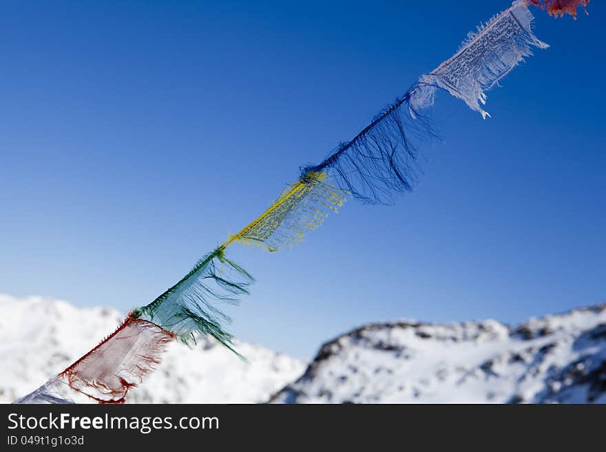 Weather-beaten lungta-style prayer flags hang in alpine mountains in Switzerland. Weather-beaten lungta-style prayer flags hang in alpine mountains in Switzerland