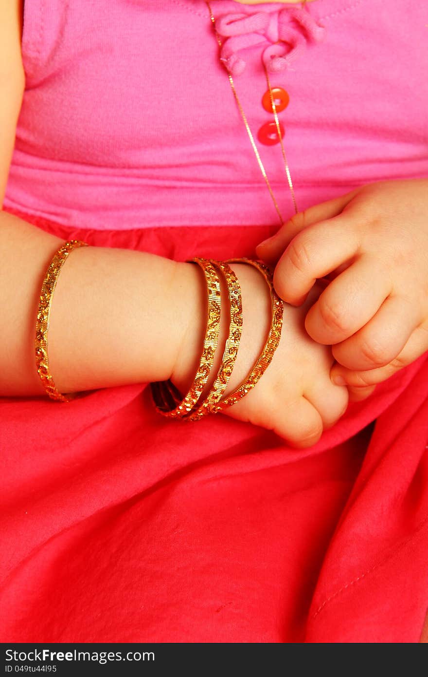 Baby hands, with golden bracelets, towards dark red