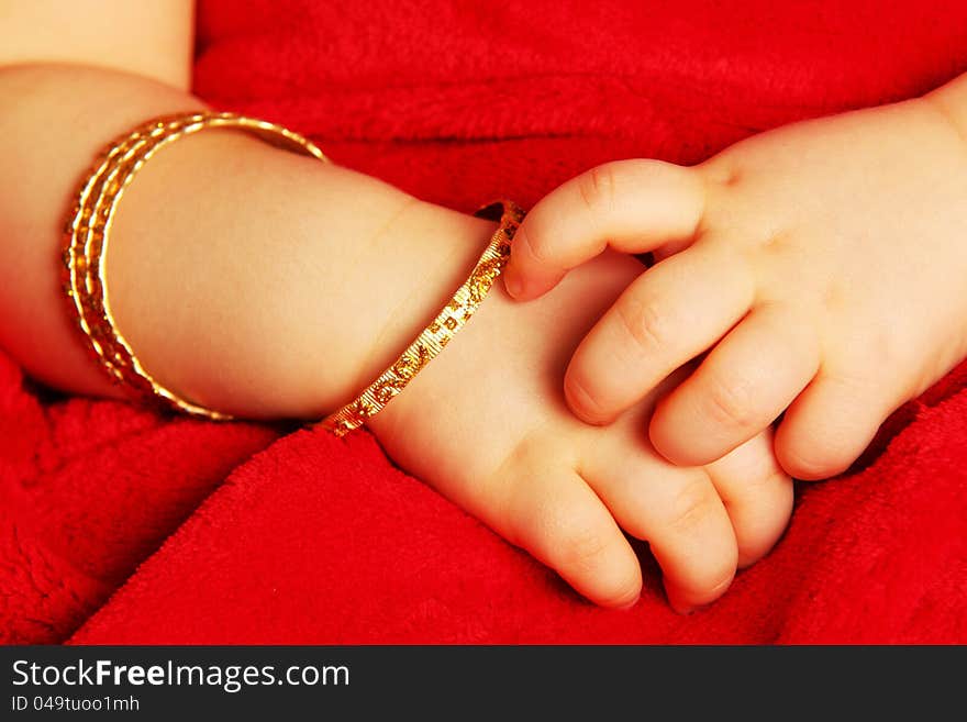 Baby hands, with golden bracelets,  towards dark red