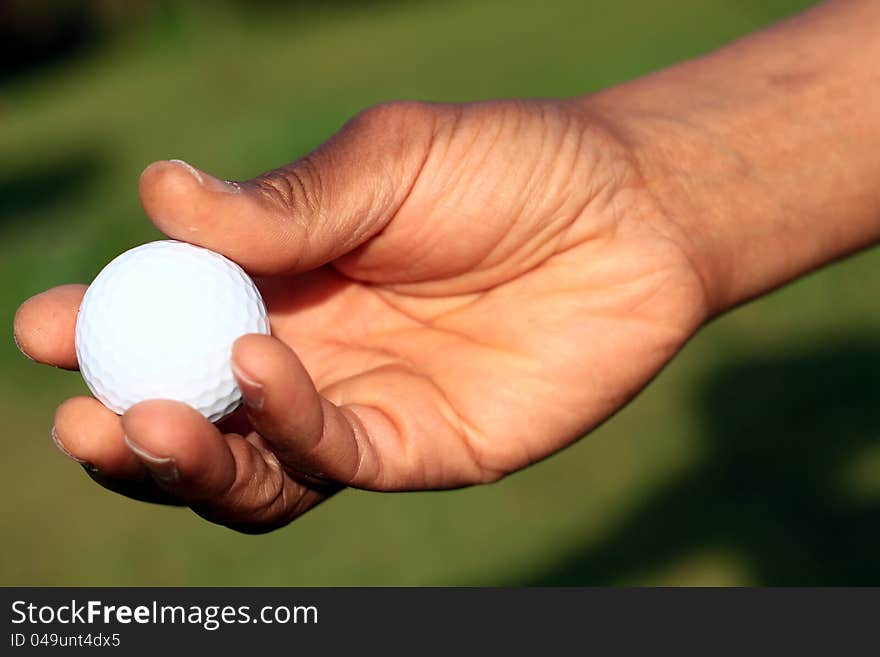 Image of a Golf ball and hand on a green background