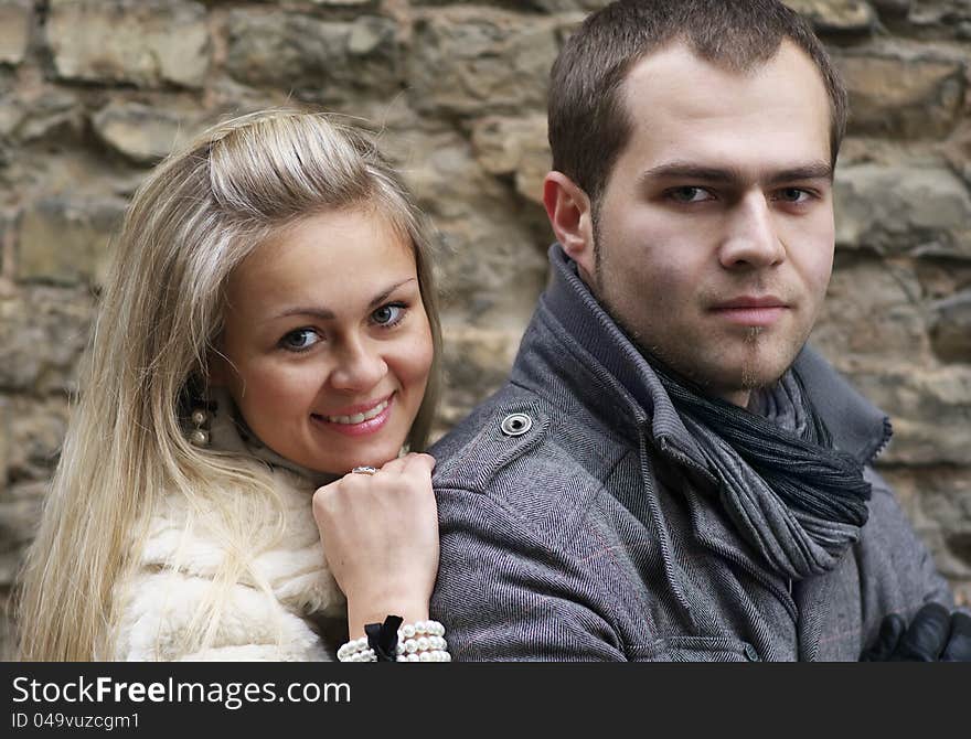 Young Woman Smiling From Behind Her Boyfriend Near Old Brick Wall