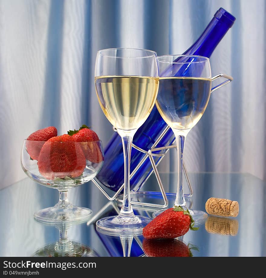 Two glasses of wine, dark blue bottle and strawberries