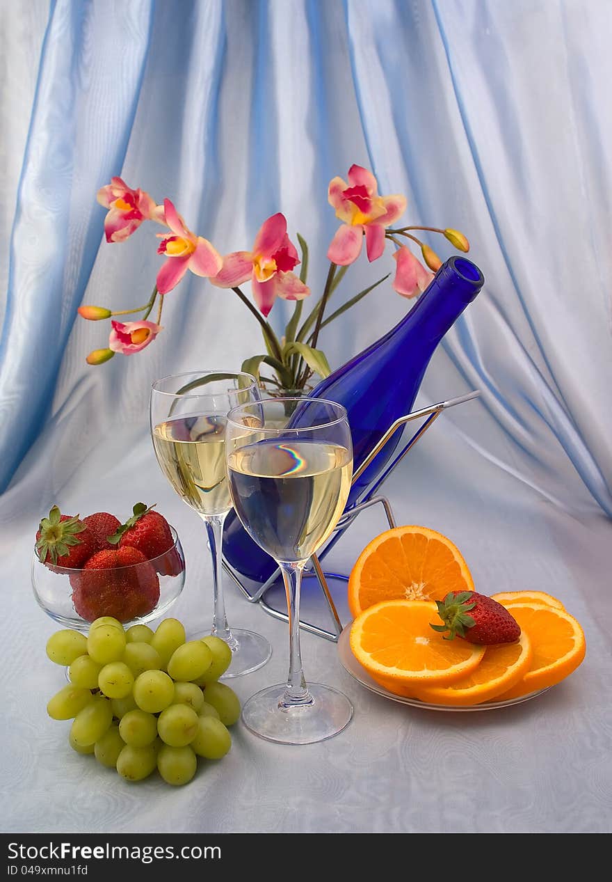 Two glasses of wine with fruits and orchid