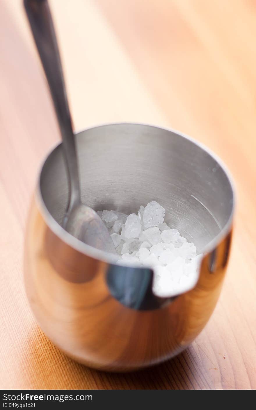 Stainless steel bowl of sugar on wood background