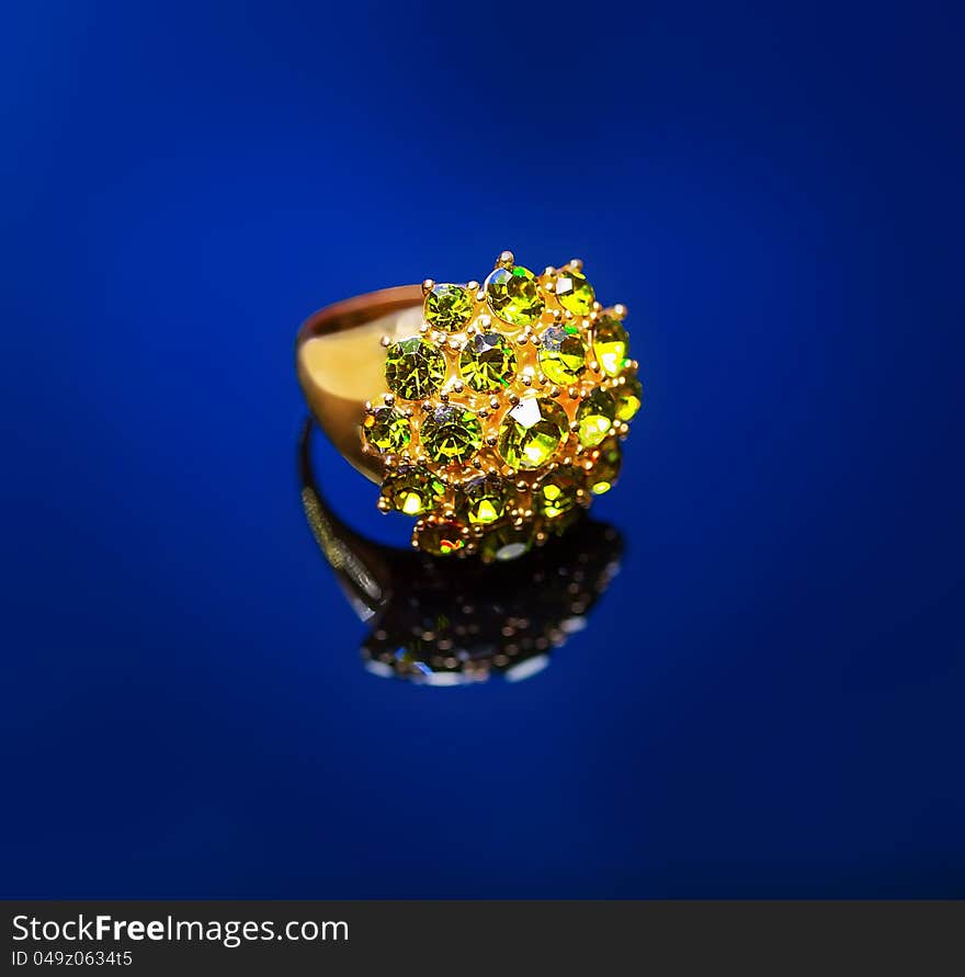 Ring with green emerald on a blue background. Ring with green emerald on a blue background