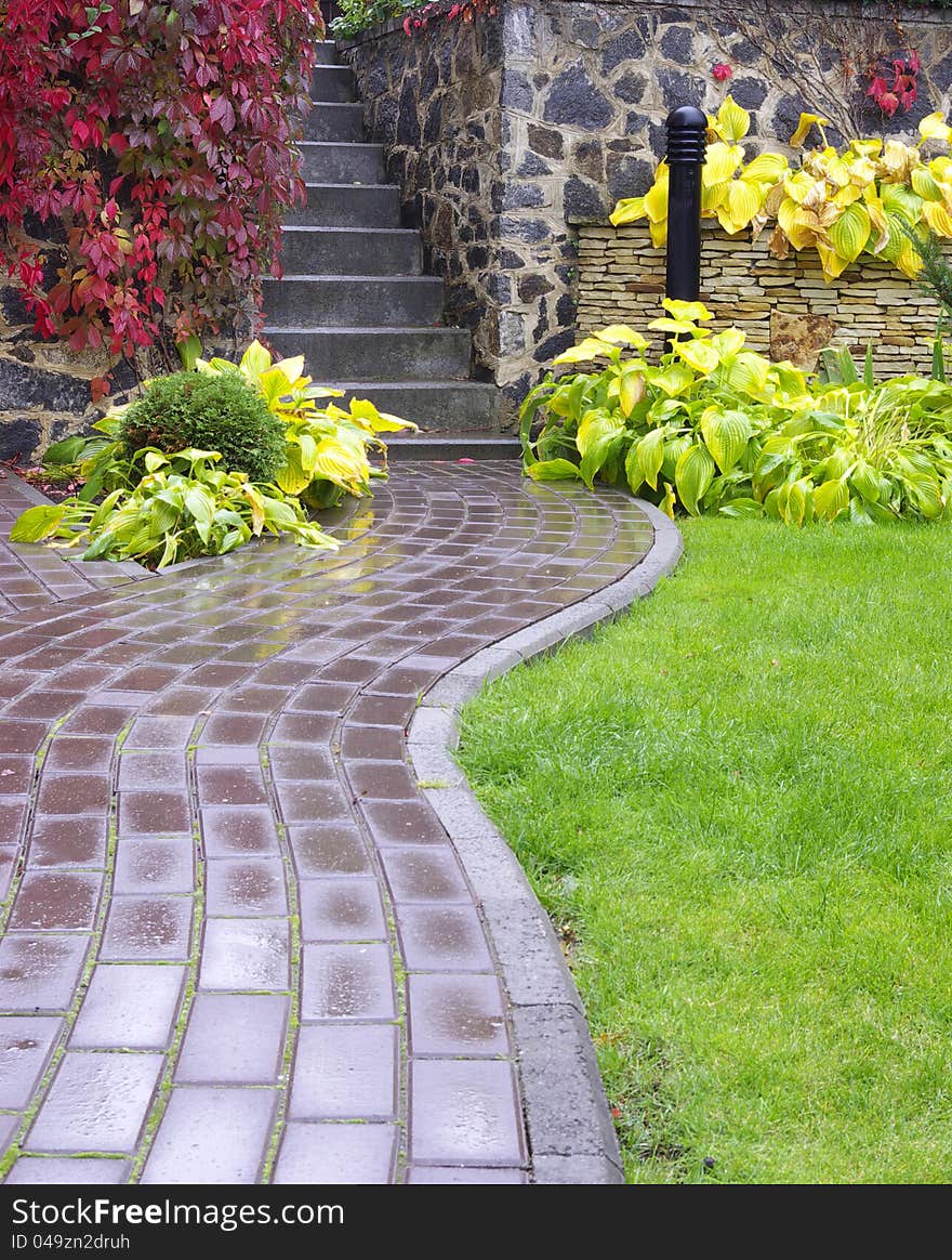 Garden stone path with grass growing up between the stones