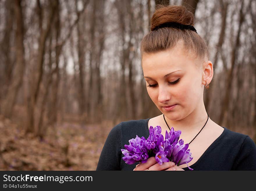 Beautiful girl with snowdrops in a forest