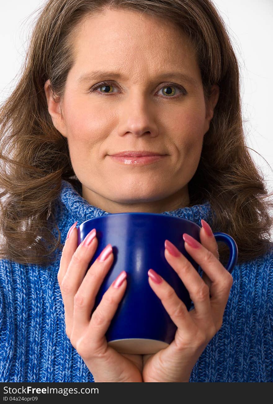 Closeup of a beautiful caucasian woman in her 40s holding a nice blue cup of warm beverage. Closeup of a beautiful caucasian woman in her 40s holding a nice blue cup of warm beverage