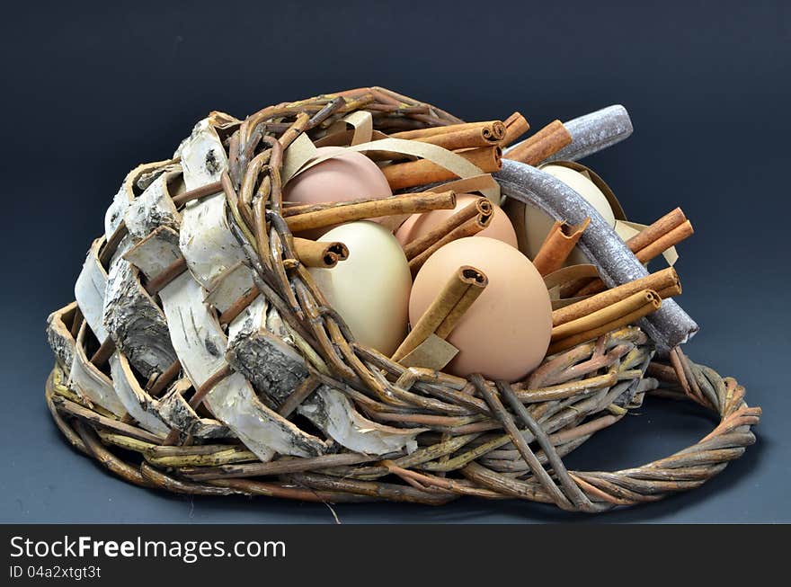 Basket of organic free-range eggs with candy and cinnamon sticks. Basket of organic free-range eggs with candy and cinnamon sticks