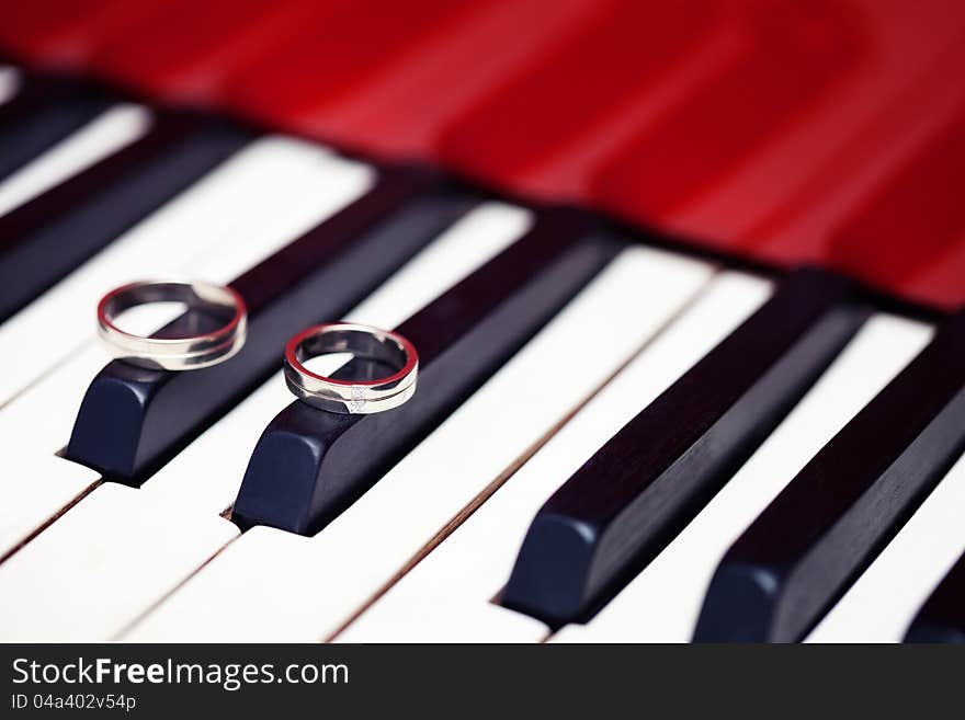 Silver wedding rings at the piano keyboard