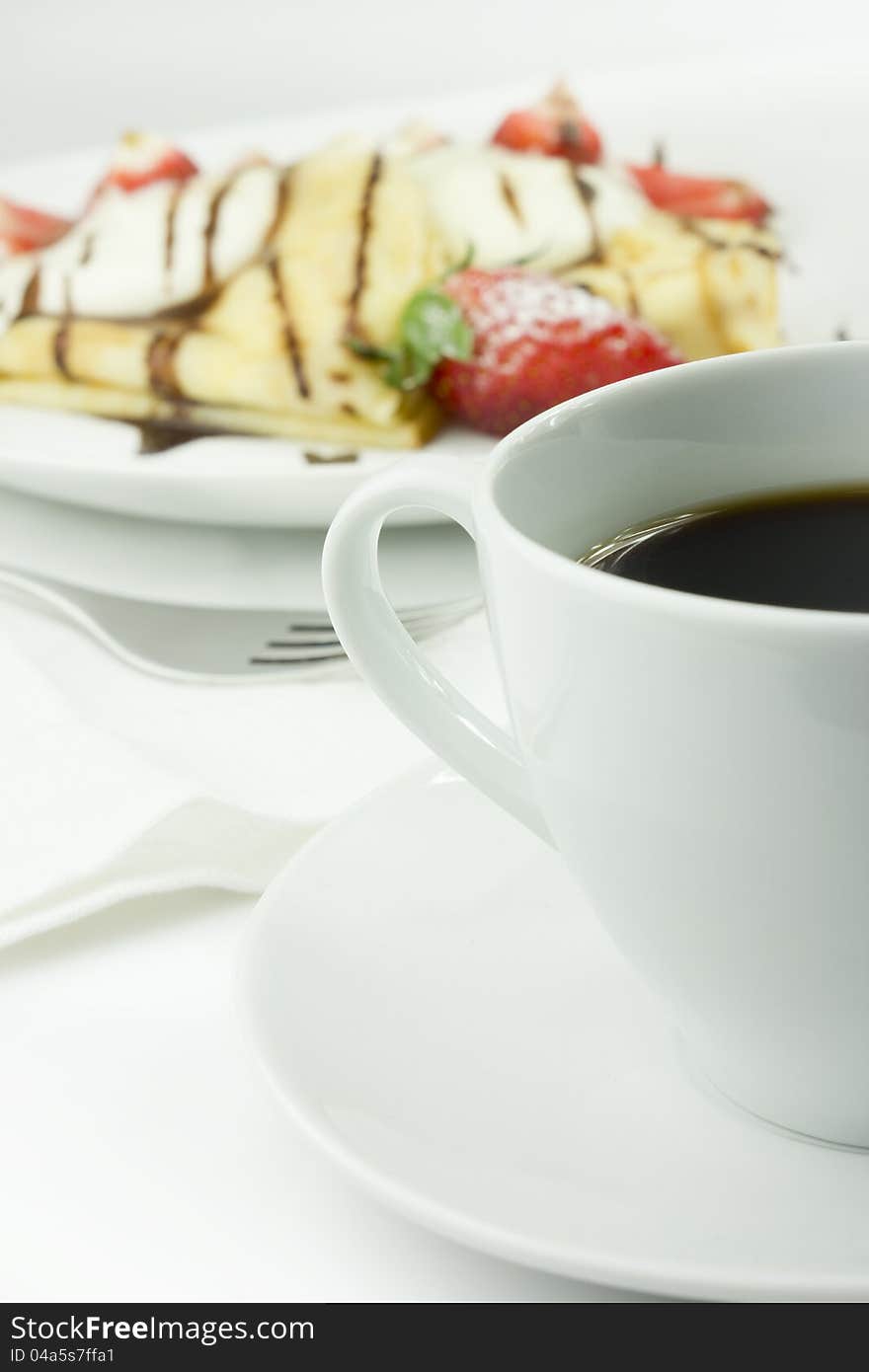 Coffee with strawberry pancake in background. Coffee with strawberry pancake in background