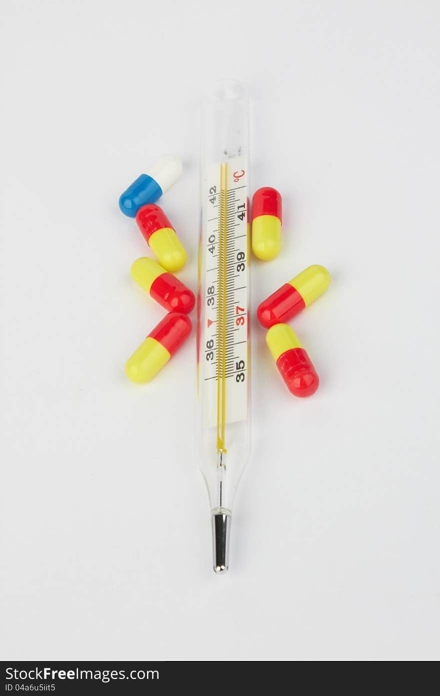 Thermometer and pills on white