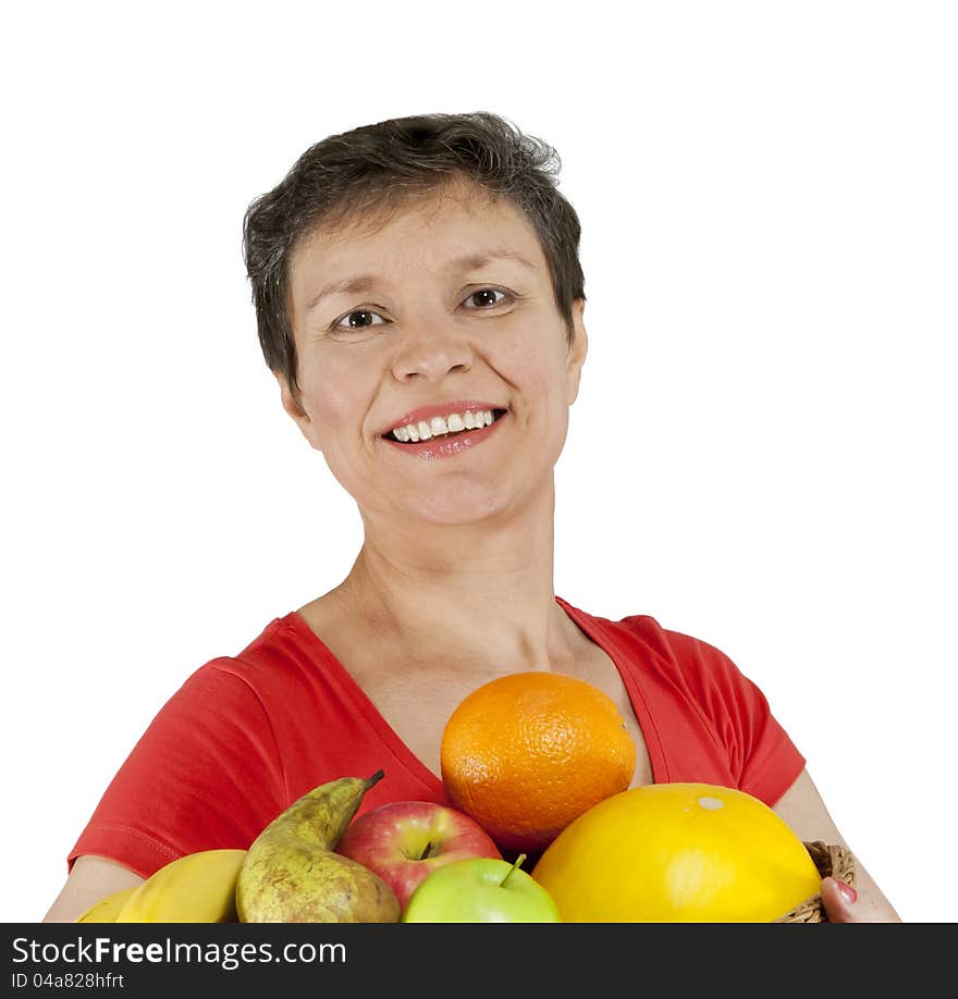 A happy smiling middle-aged woman holding a basket full of fruits. Isolated over white.