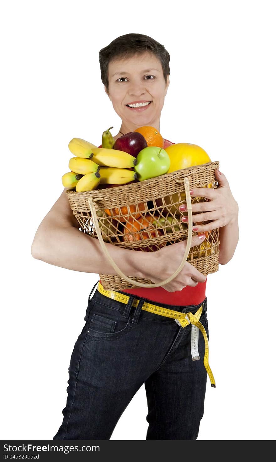 A happy smiling middle-aged woman holding a basket full of fruits. Isolated over white.