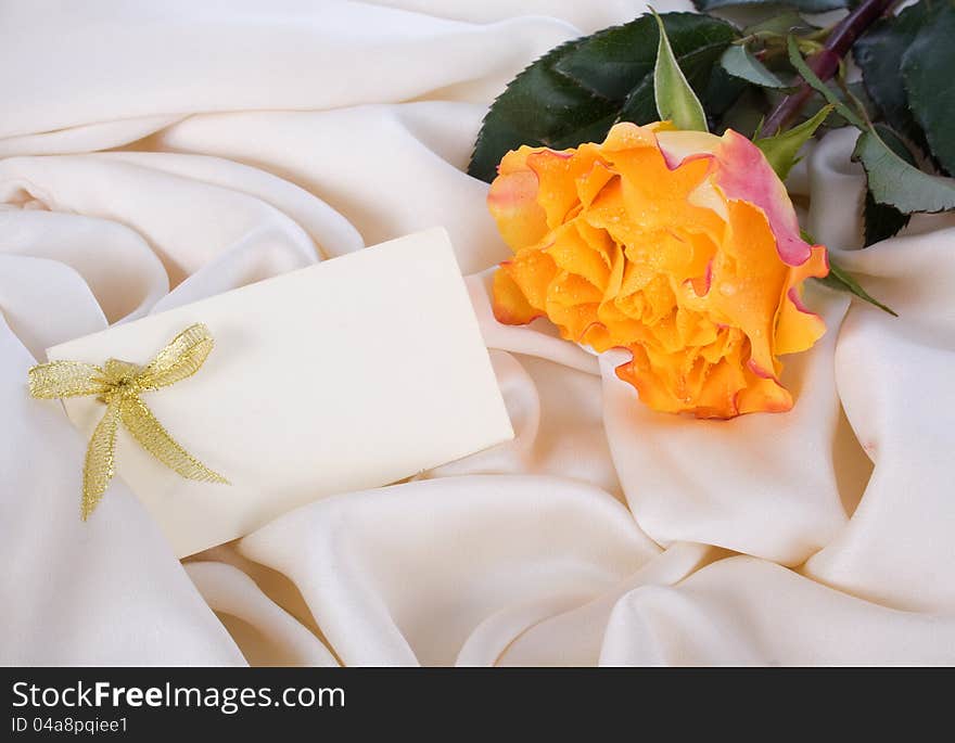 Yellow rose and a card on a gentle silk