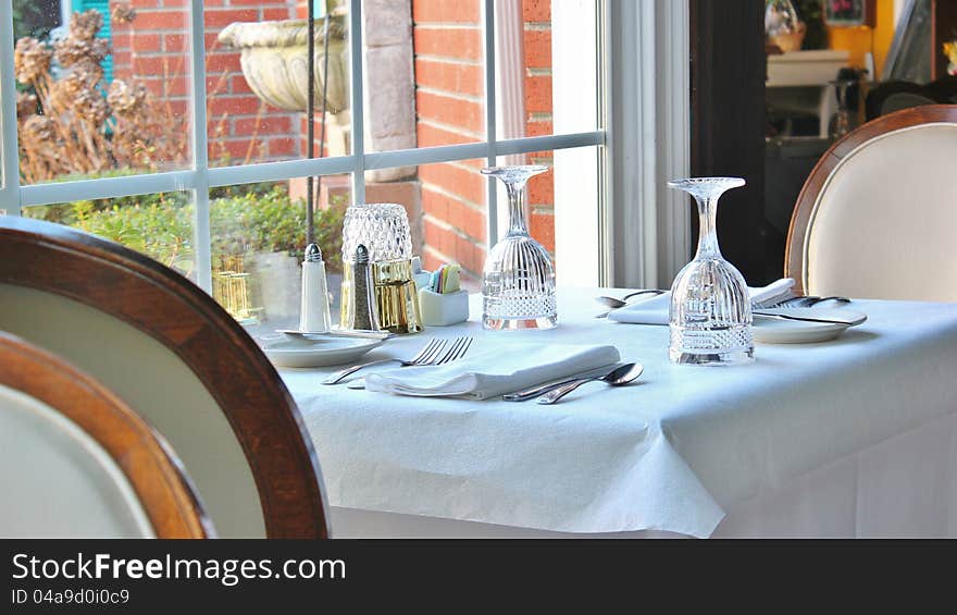 A table for two by a brightly lit window. A table for two by a brightly lit window