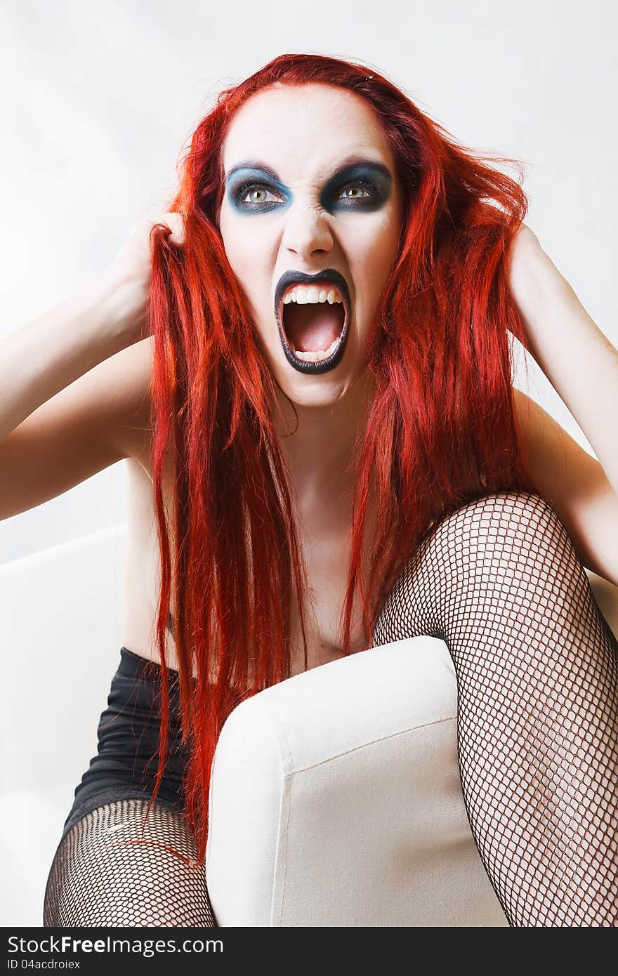 Studio shot of expressive gothic red haired woman with artistic makeup over white background. Studio shot of expressive gothic red haired woman with artistic makeup over white background