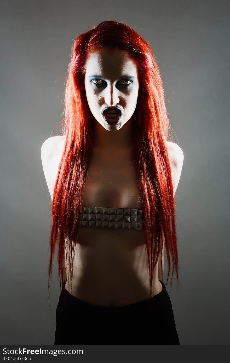 Studio shot of expressive gothic red haired woman with artistic makeup with dramatic light. Studio shot of expressive gothic red haired woman with artistic makeup with dramatic light