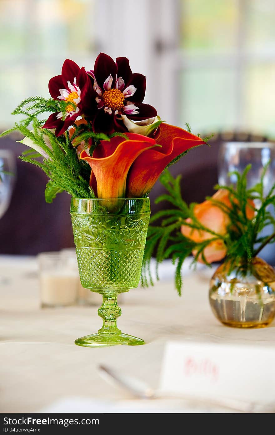 A small wedding centerpiece of flowers in a green vase