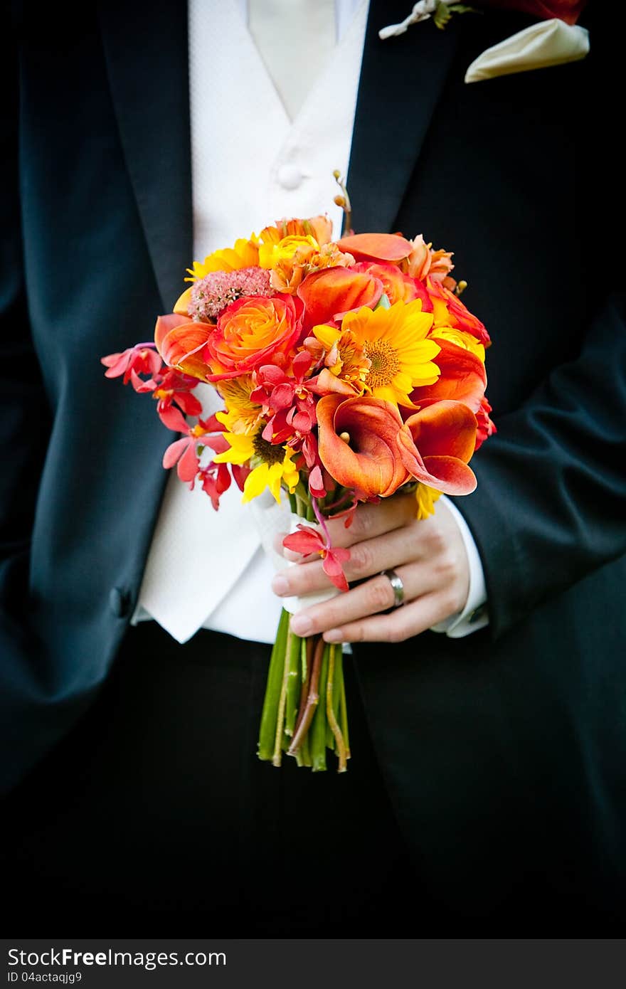 A bridal wedding bouquet of flowers being held by a groom