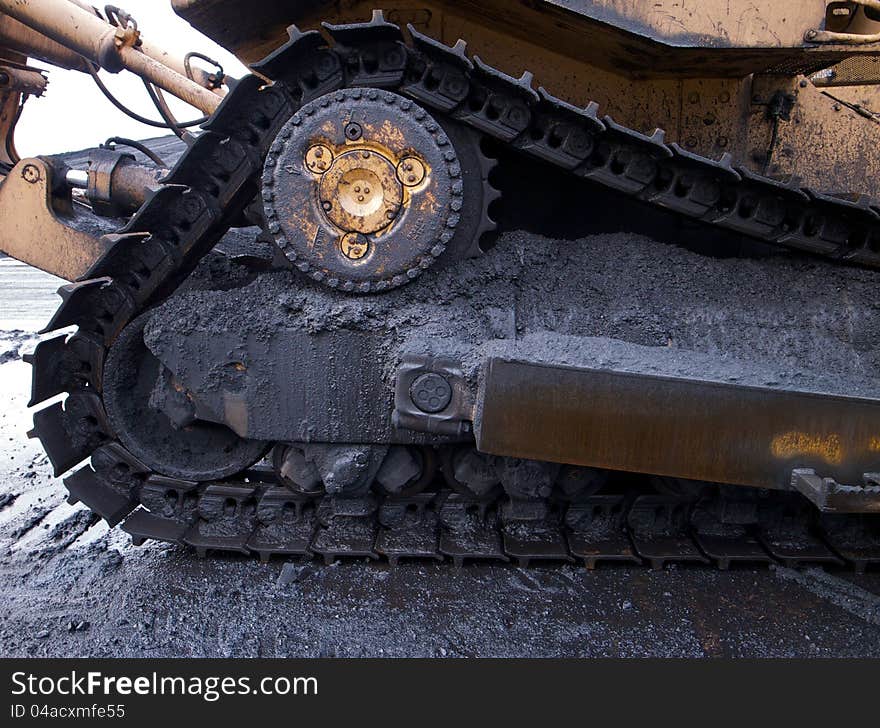 Bulldozer caterpillar tracks covered in coal dust