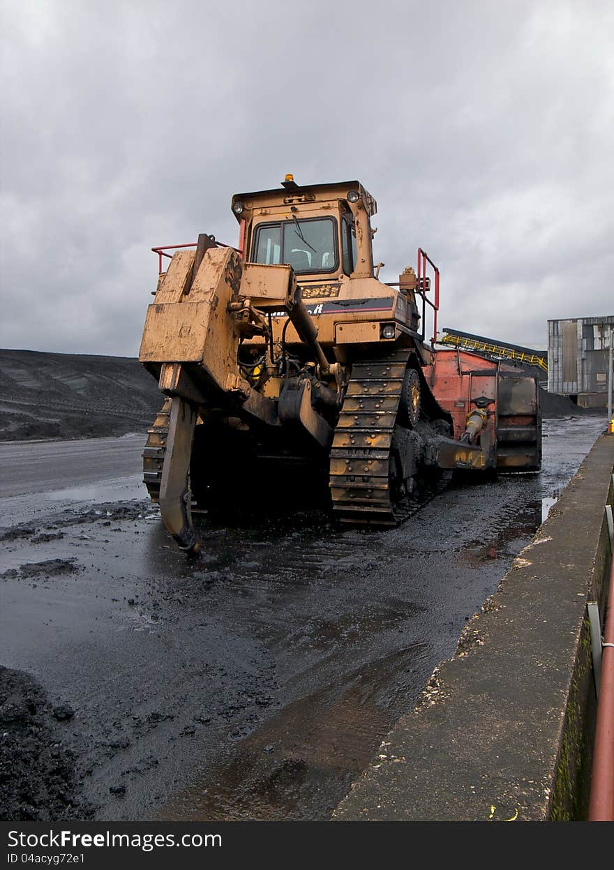 Bulldozer parked near a coal stock pile.