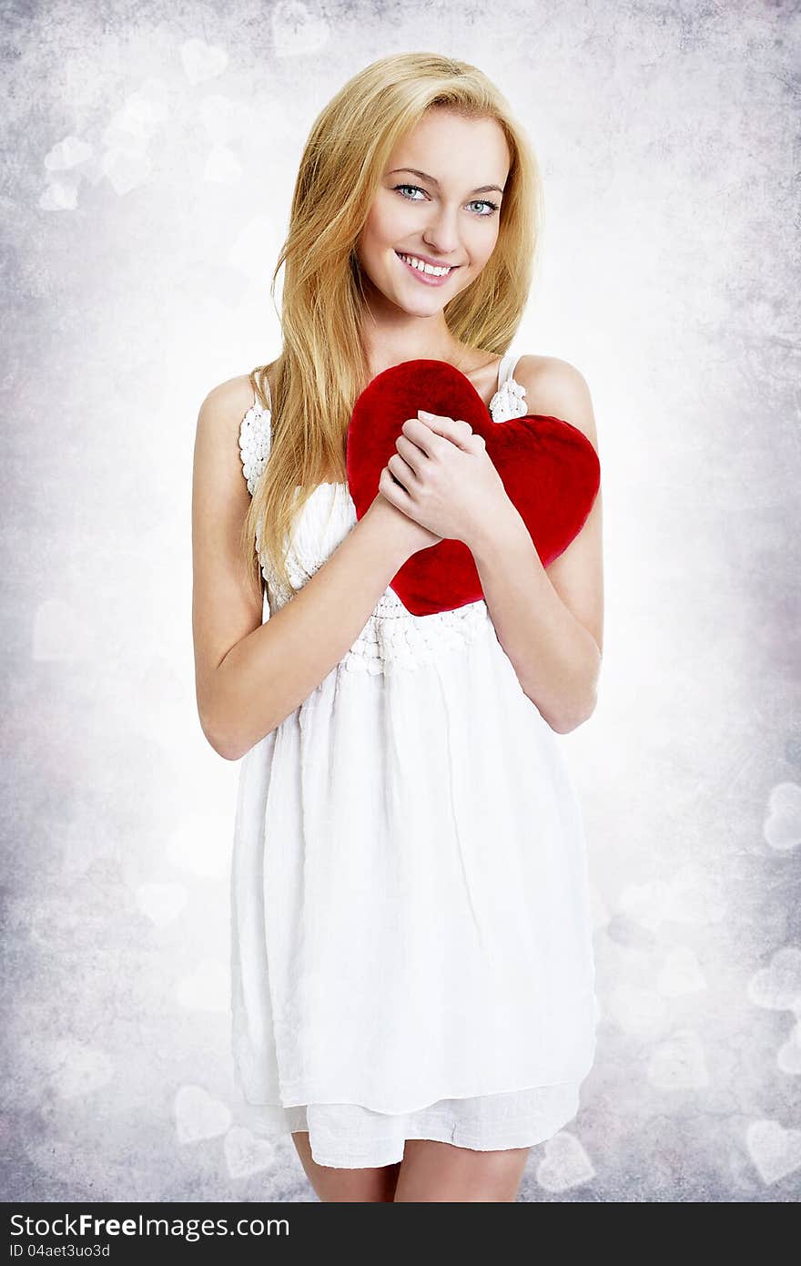 Sweet smiling young blond woman holding red heart shape pillow. Sweet smiling young blond woman holding red heart shape pillow