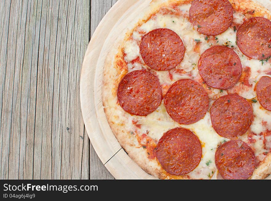 Closeup of a freshly cooked pepperoni pizza on a wooden board