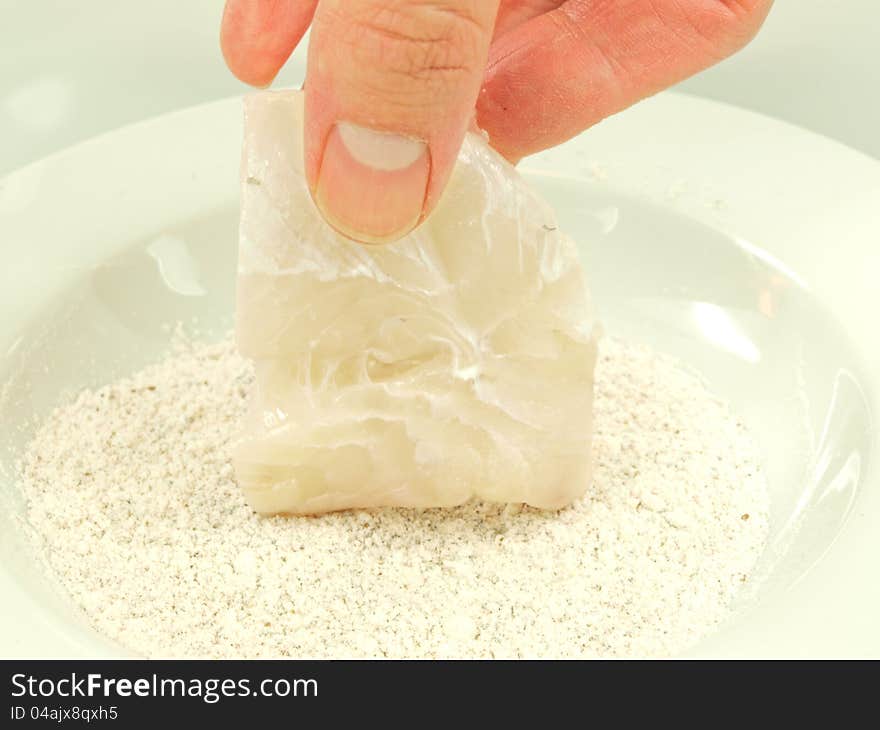 Person adding seasoning to a white fish fillet. Person adding seasoning to a white fish fillet