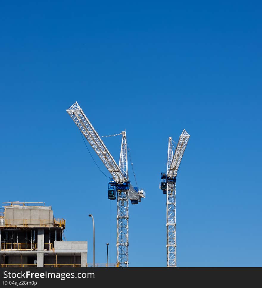 Cranes on buiding site against bright blue sky. Cranes on buiding site against bright blue sky