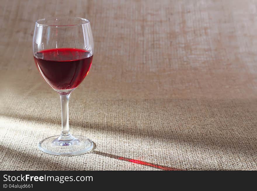 Glass of red wine against a rough sacking