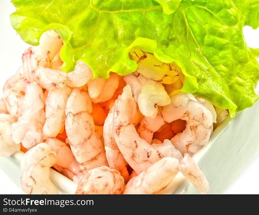 Peeled shrimps, isolated in a white bowl, lettuce on top. Peeled shrimps, isolated in a white bowl, lettuce on top