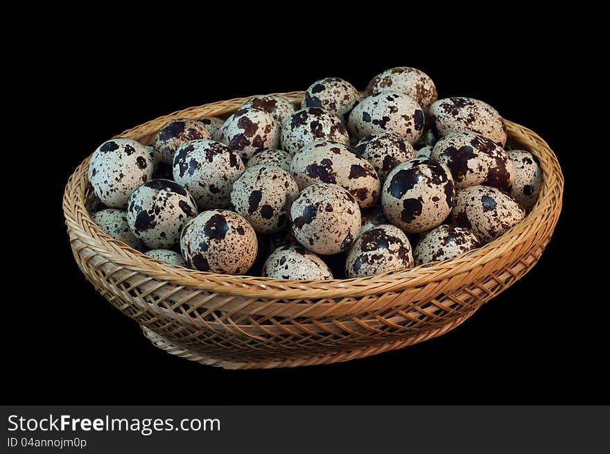 The photo shows quail eggs  close up on black background in basket