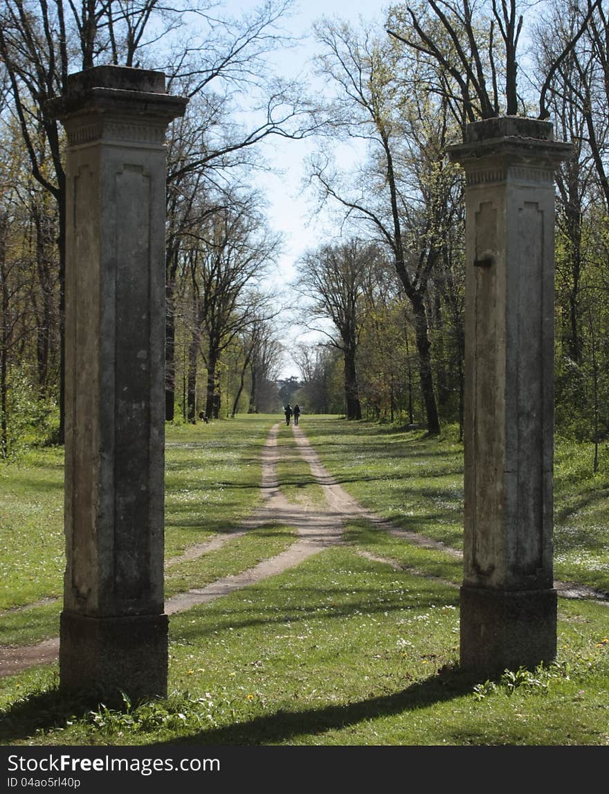 Between the remains of an old gate can a path walked by two persons that can be seen at distance. Between the remains of an old gate can a path walked by two persons that can be seen at distance