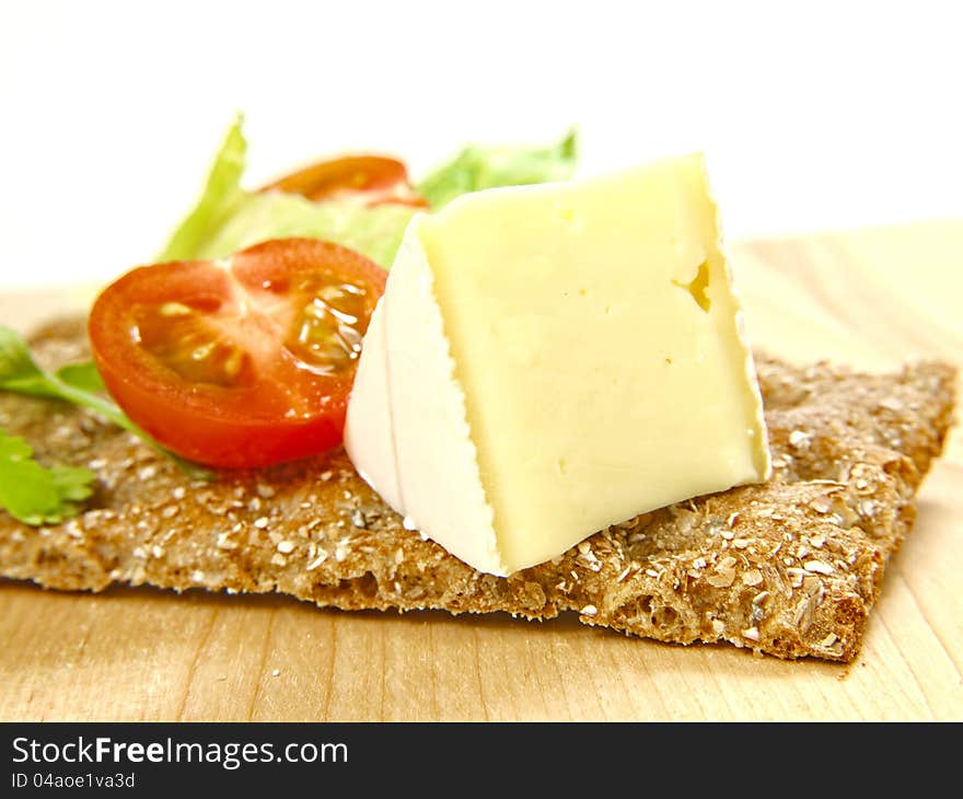 Cracker on wooden board, with soft cheese and tomato. Cracker on wooden board, with soft cheese and tomato