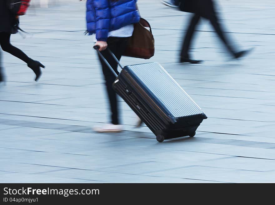 Travelling person with a trolley case. The photo was taken by panning the camera for show the motion in blur