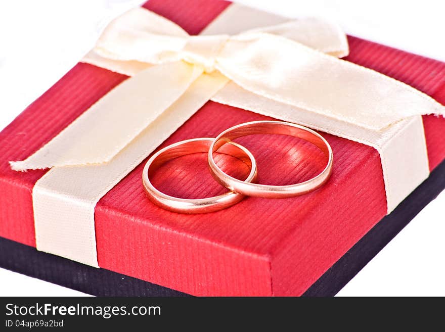 Golden wedding rings near the red gift box Isolated on white background