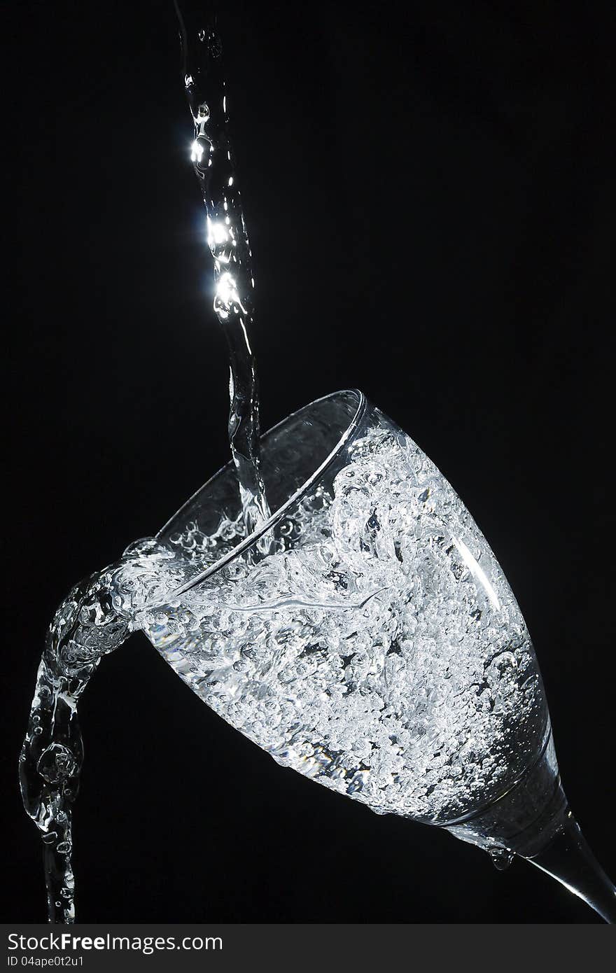 Sparkling water pouring into glass against a black background. Sparkling water pouring into glass against a black background