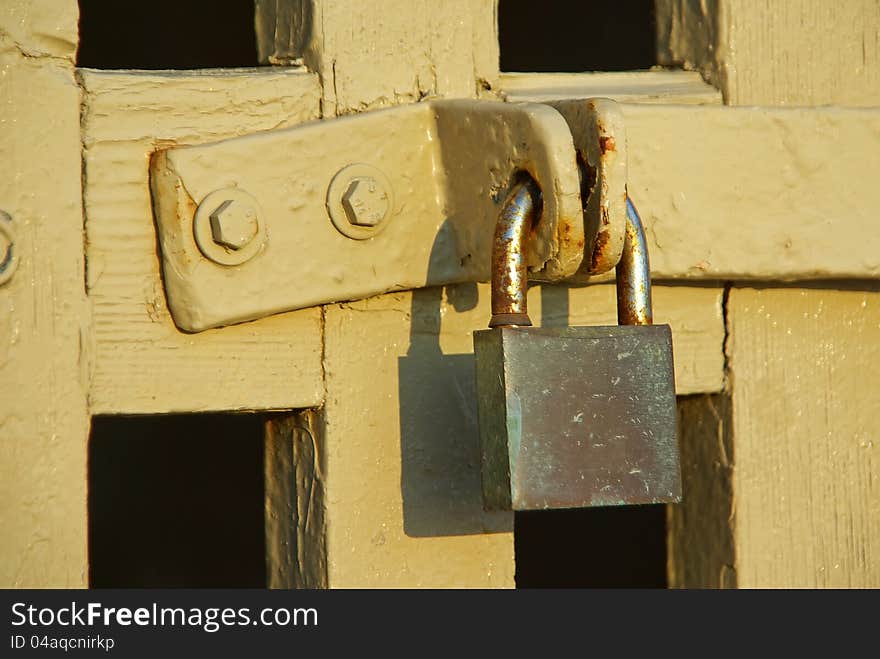 Rusty padlock closing a wooden yellow fence