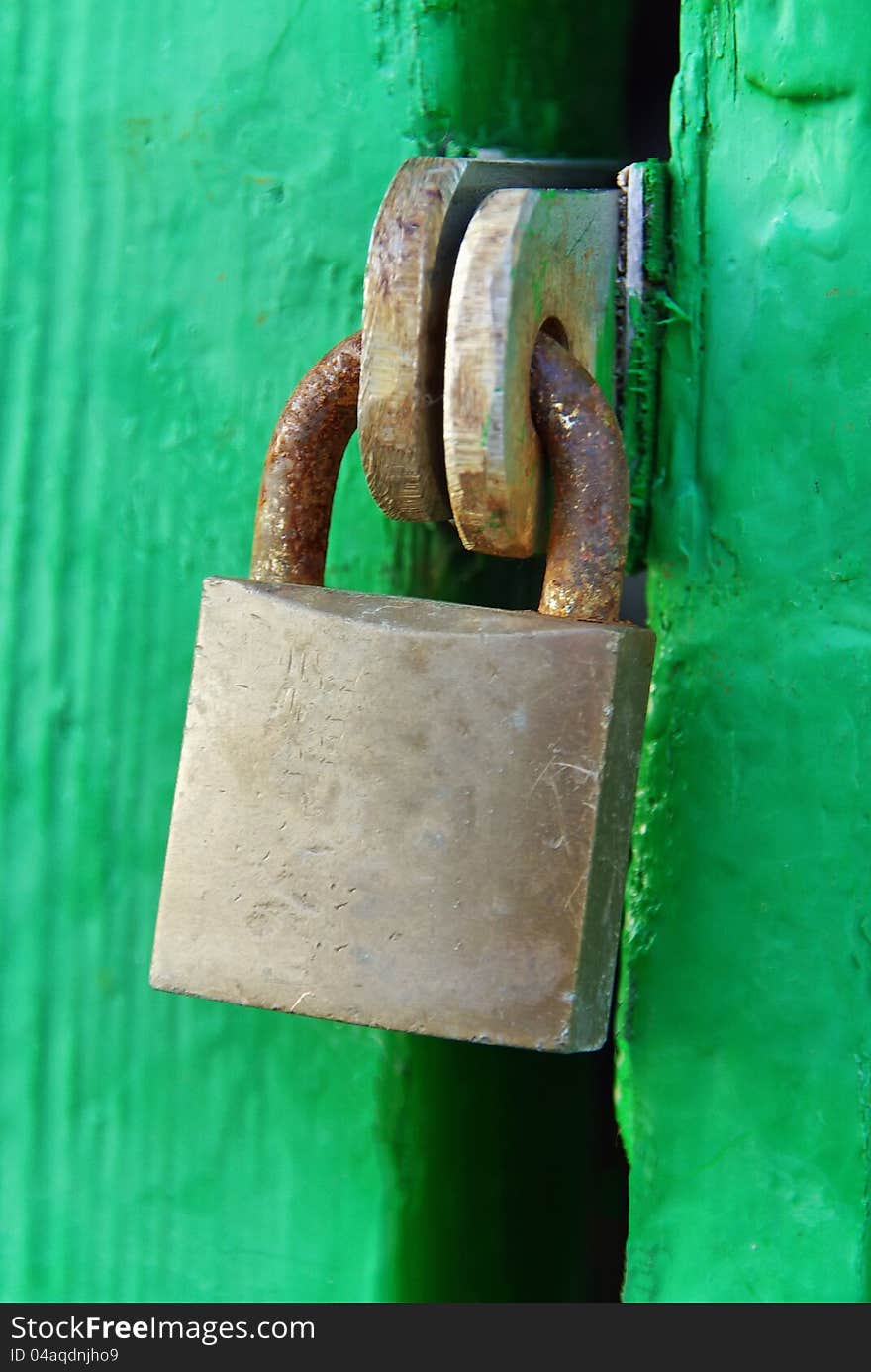 Rusty Padlock on a green wooden door