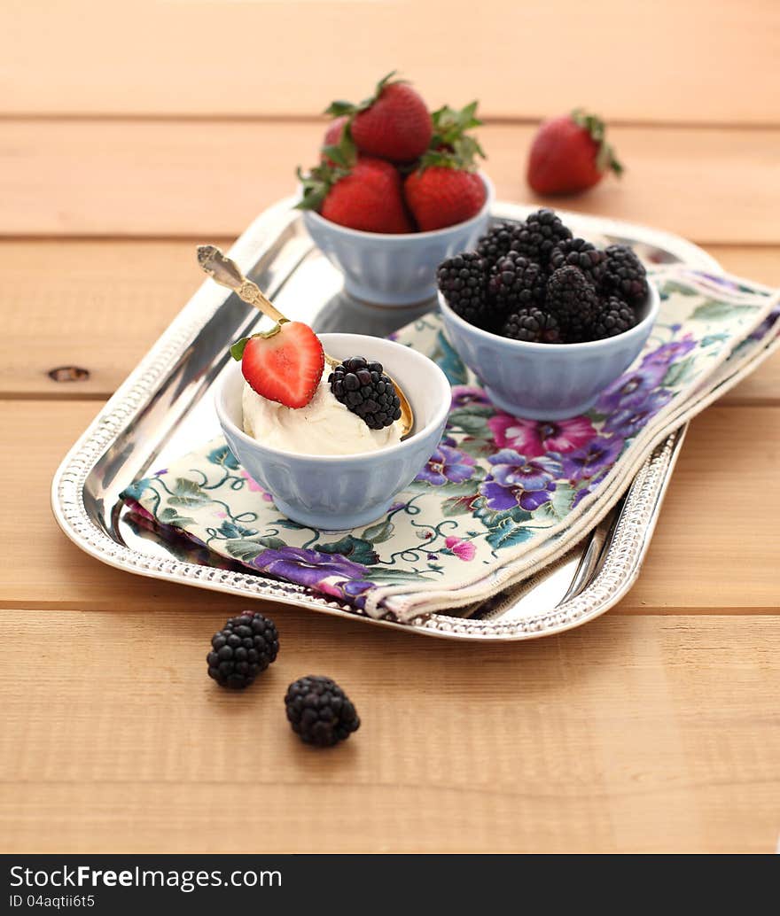 Strawberries and blackberry with mascarpone cream on a tray with a napkin