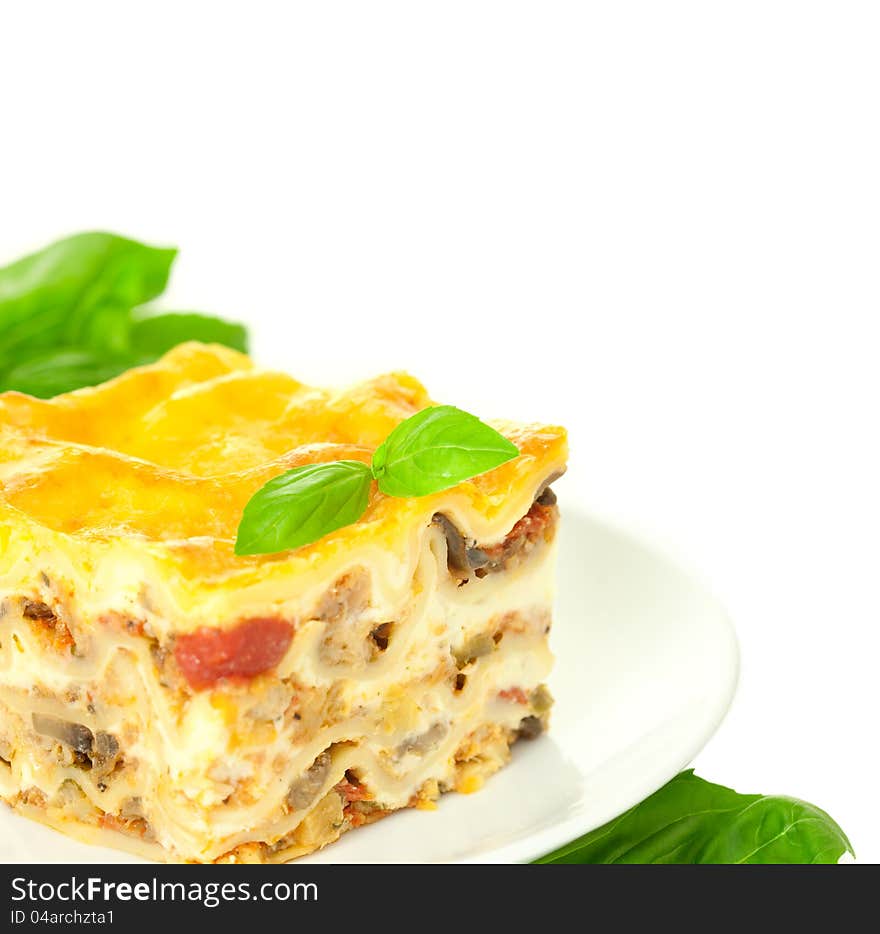 Portion of Classic Lasagna Bolognese with basil herb / isolated on white / corner composition