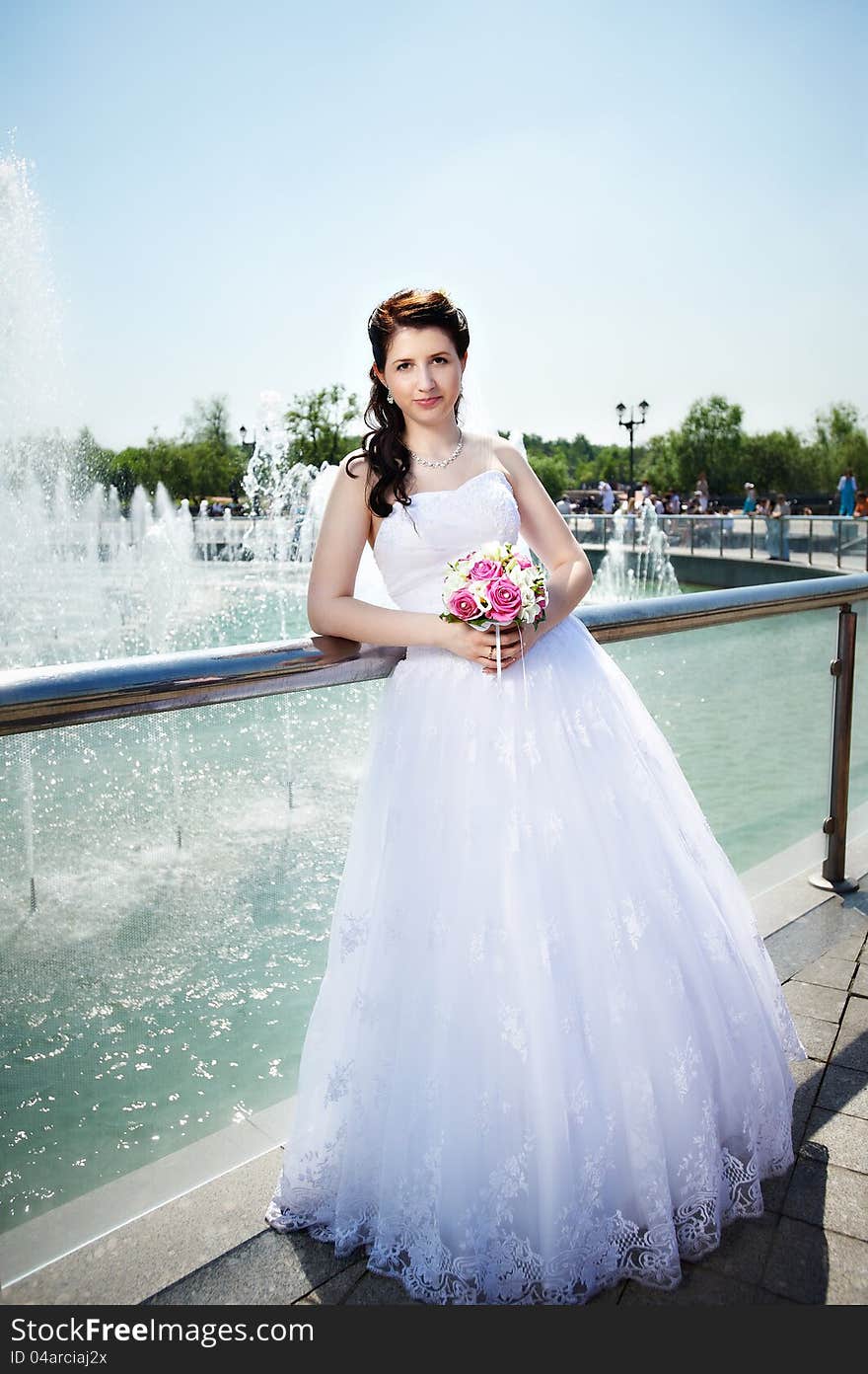 Happy bride about fountain with bouquet