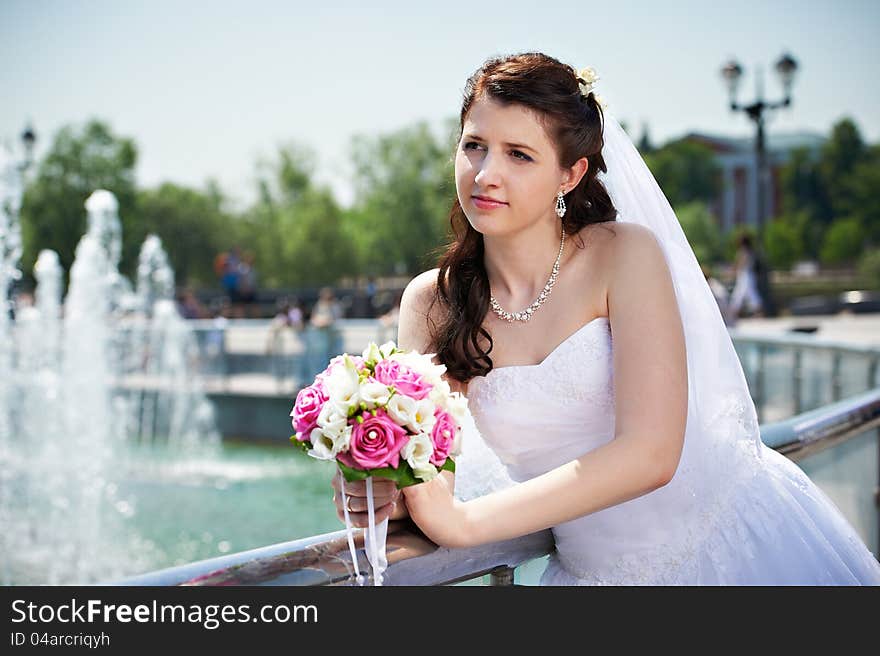 Happy Bride About Fountain With Bouquet