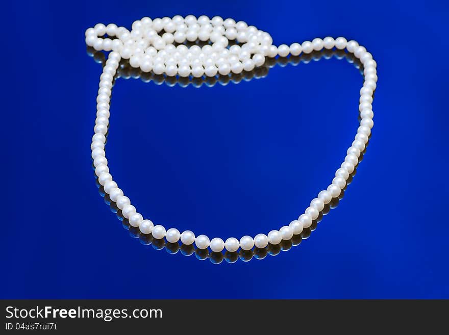 Necklace with white pearl on a blue background. Necklace with white pearl on a blue background