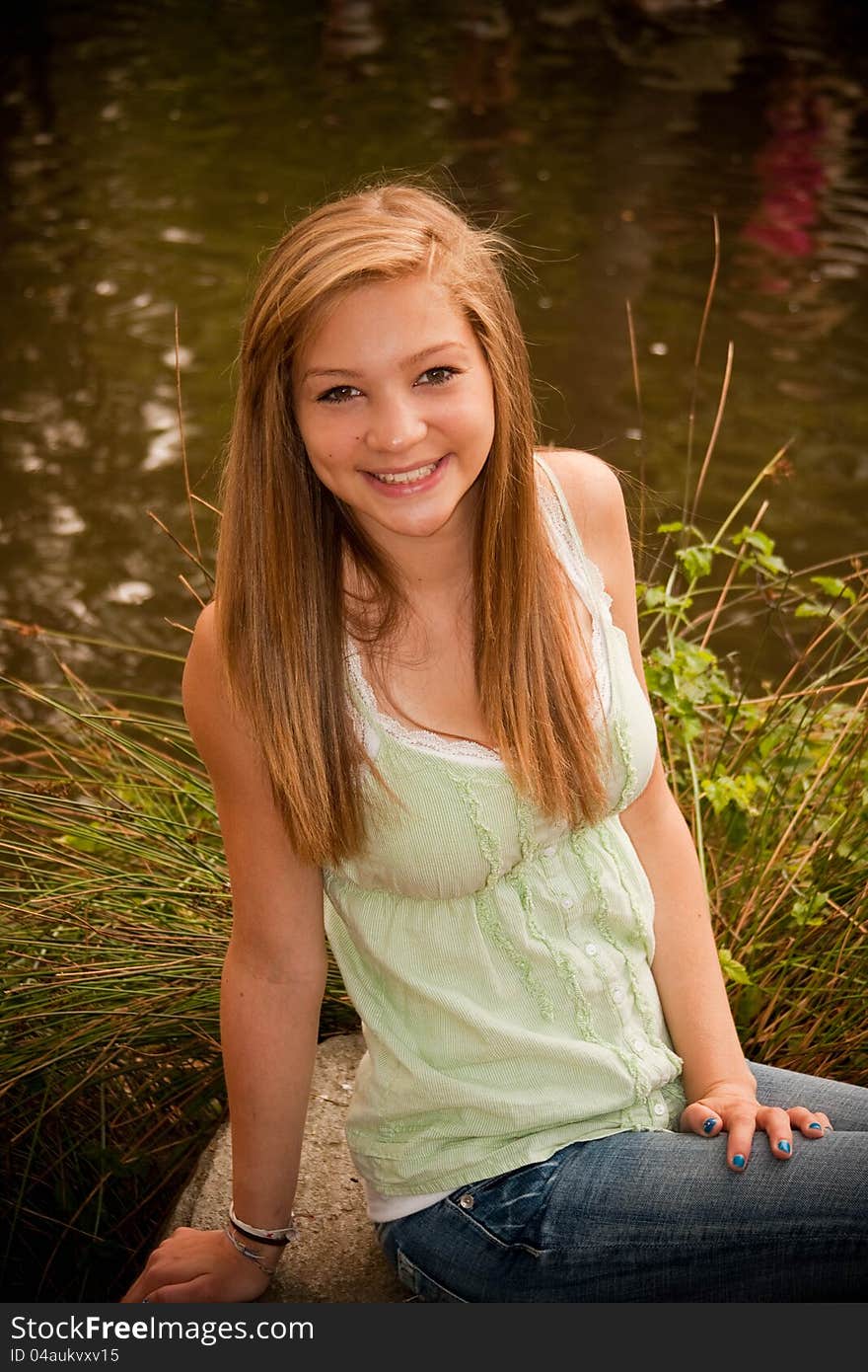 Teen girl sitting at pond